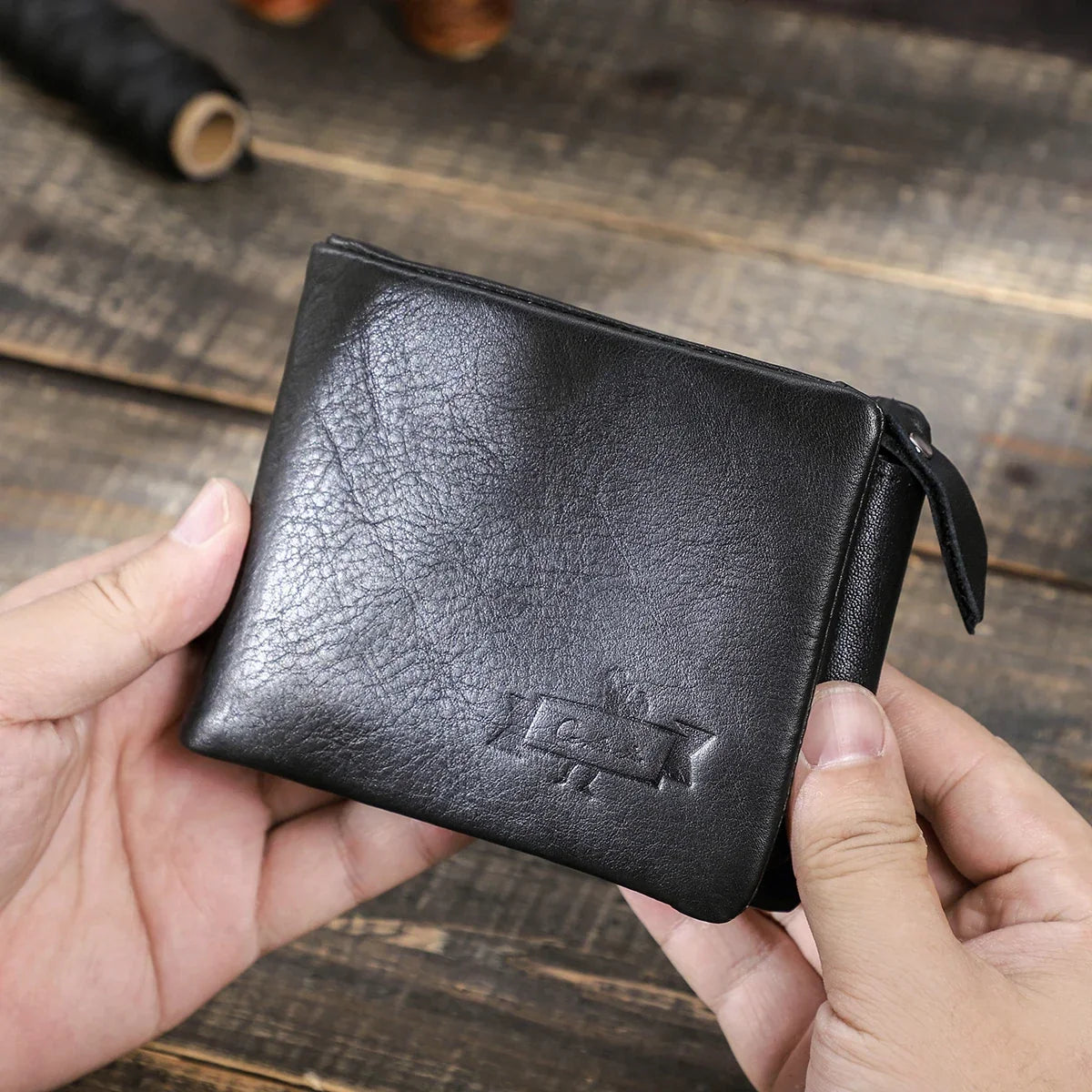 Portefeuille Marius en cuir noir, aperçu du format tenu en main