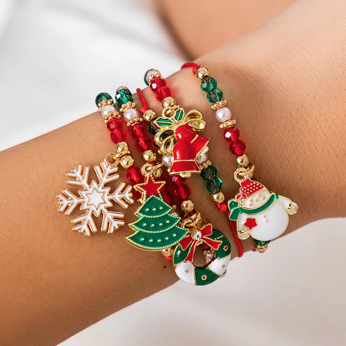 Lot de cinq bracelets Noël Enchanté à cordons rouges et breloques de Noël porté au poignet